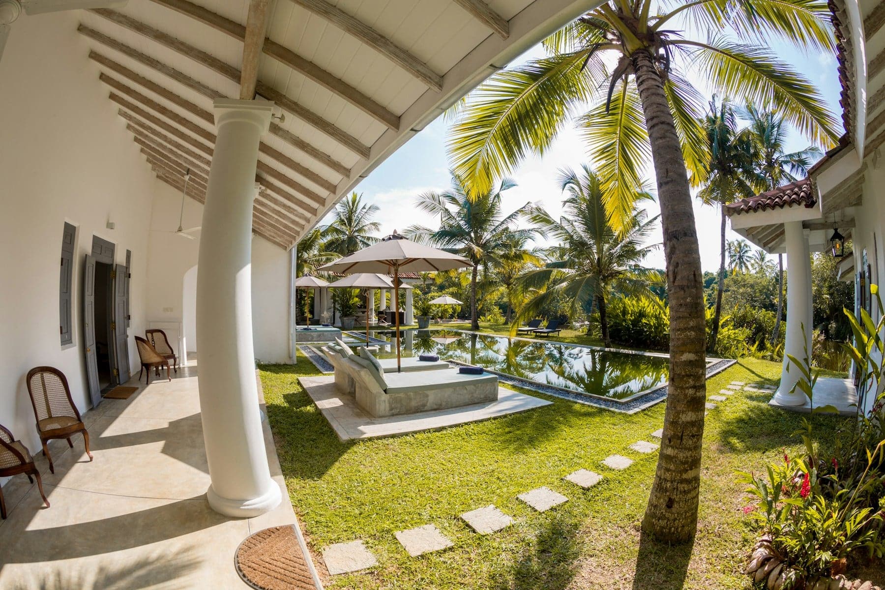 Colonial-style veranda with white pillars overlooking a tropical garden