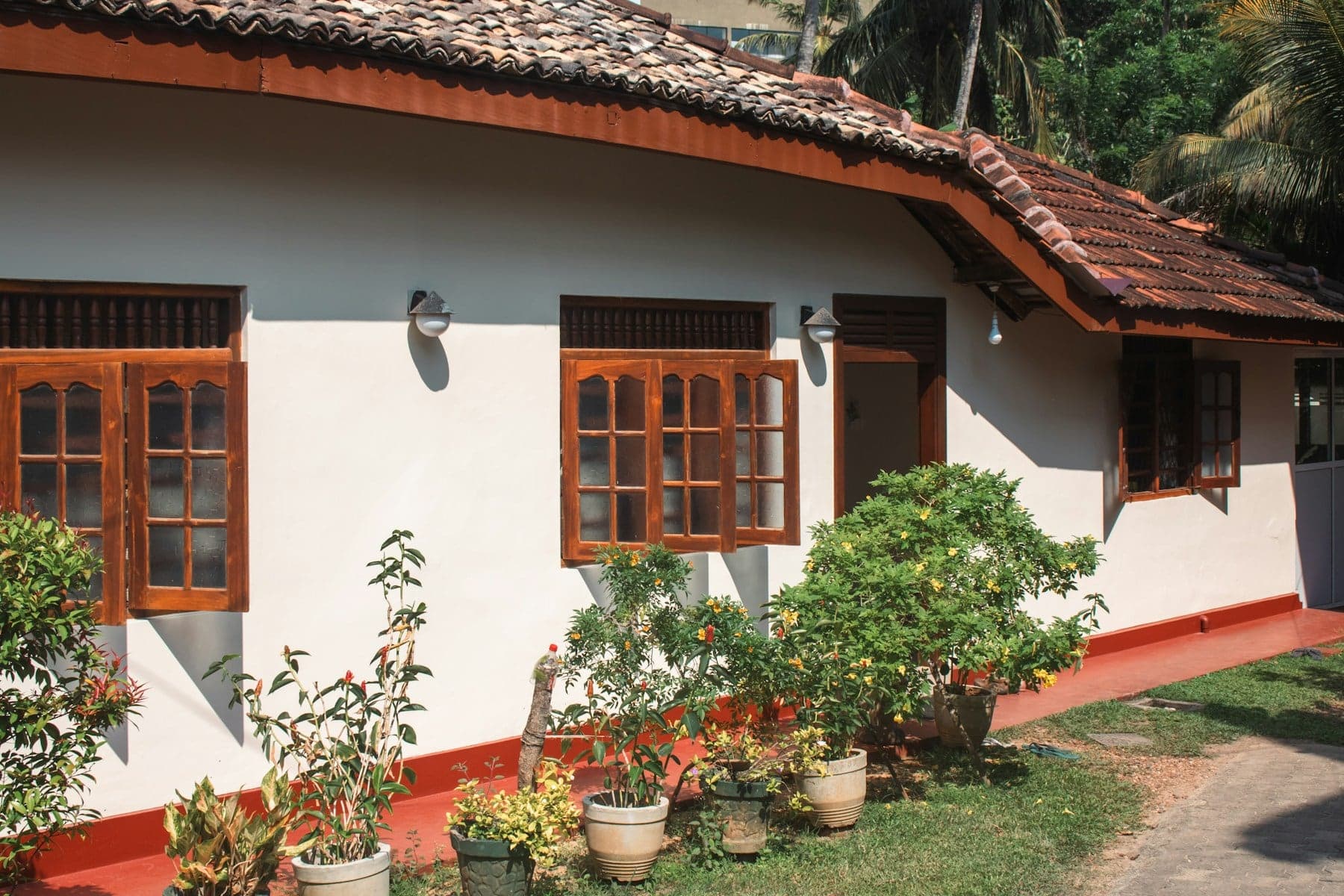 Classic Sri Lankan home with a red tiled roof, timber windows and a flower garden